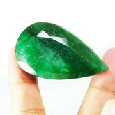 Large emerald gemstone held between two fingers